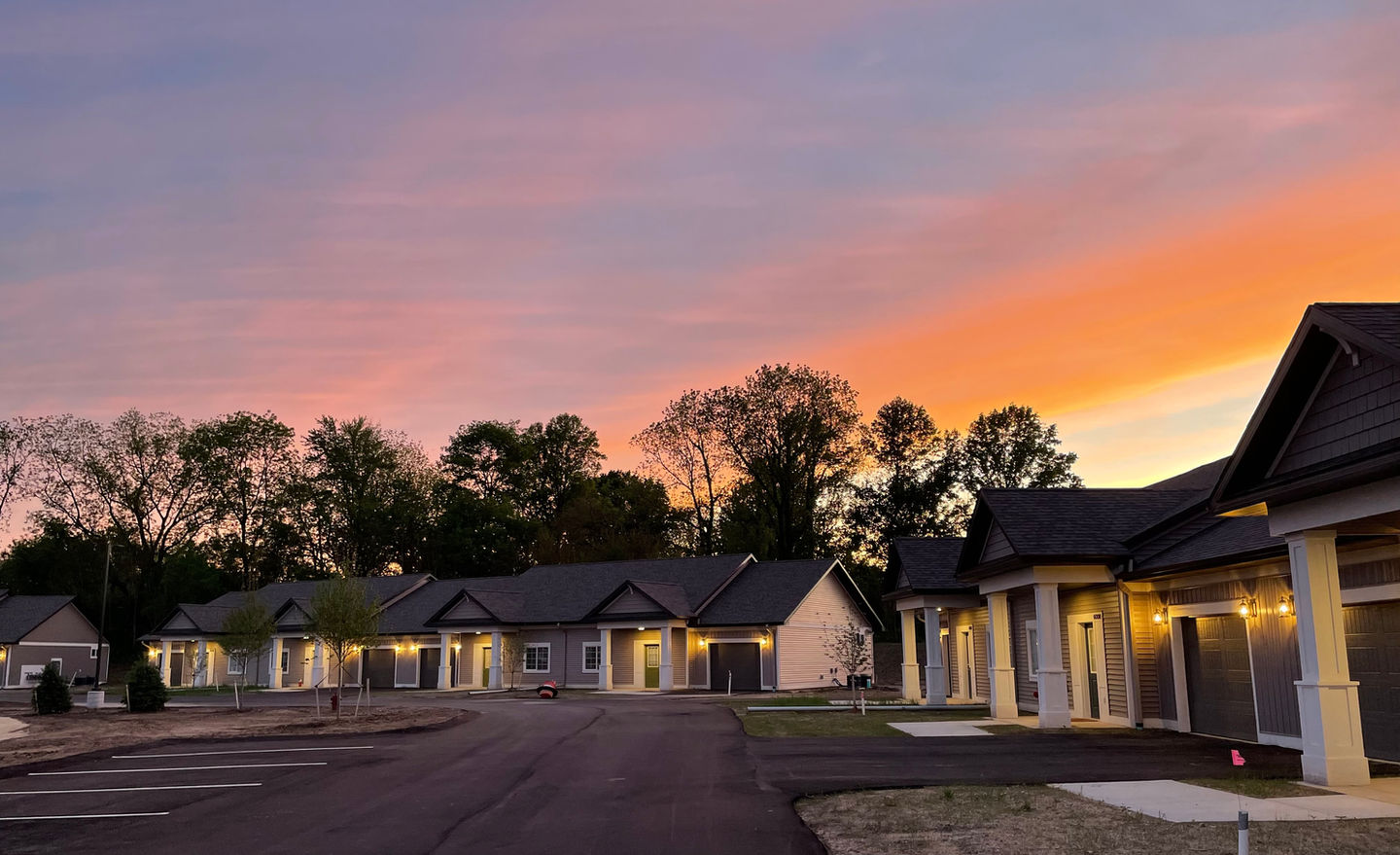 Single-storey senior living community at dusk with warm lit entries